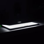 A dramatic, low-light image of a slightly open laptop with glowing keys on a dark desk.